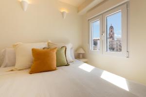 a white bedroom with a large bed with a window at Ático 360º con Piscina in Málaga +35 photos