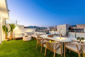 a rooftop patio with white tables and chairs and grass at Ático 360º con Piscina in Málaga