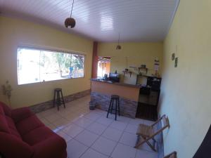 a living room with a red couch and a kitchen at Pousada Solaris in Bonito