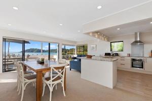 a kitchen and living room with a table and chairs at Spectacular Woolleys Bay in Matapouri