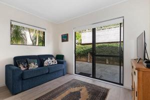 a living room with a blue couch and a sliding glass door at Spectacular Woolleys Bay in Matapouri