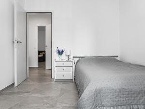 a white bedroom with a bed and a white dresser at Appartamento Rivamaggia Locarno in Solduno