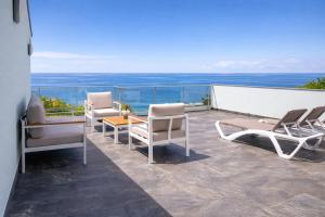 a group of chairs and tables on a balcony at Villa O Pomar with optional heated pool in Paul do Mar +13 photos