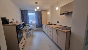 a kitchen with white cabinets and a table and a window at Solovan Hill in Sighetu Marmaţiei