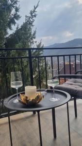 a table with two glasses and a candle on a balcony at Solovan Hill in Sighetu Marmaţiei
