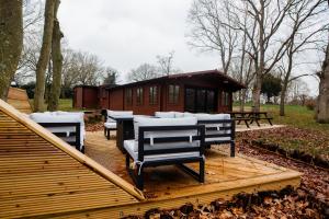 a group of benches sitting on a wooden deck with a cabin at Countryside Cabin on 5 Acres Countryside with Outdoor Firepit, Cinema and converted Stables in Sible Hedingham