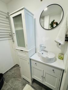 a white bathroom with a sink and a mirror at Apartament UNO in Reşiţa