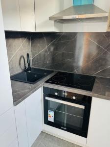 a kitchen with a black stove and white cabinets at Apartament UNO in Reşiţa