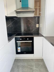 a kitchen with white cabinets and a black oven at Apartament UNO in Reşiţa +4 photos