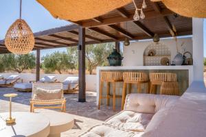 a patio with a couch and tables and chairs at Finca las Calmas Adults Only Boutique Retreat & Dining Experience in Moraleda de Zafayona