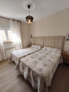a white bedroom with two beds and a lamp at La Fuentona in Celorio