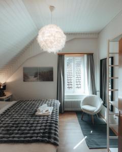 a bedroom with a bed and a chair and a chandelier at LaVida LakeSoul Cozy Retreat in Murten am See & Altstadt, free parking in Murten