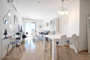 a dining room and living room with a white table and chairs at Panoramic Sea View Cabo Roig in Orihuela Costa