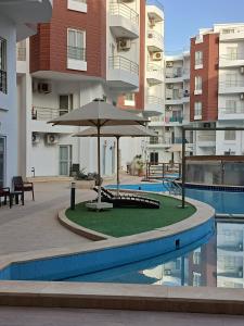 a patio with an umbrella next to a swimming pool at Aqua Palms Resort D101 in El Gouna