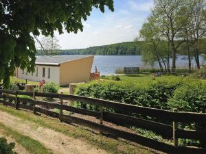 a house with a fence next to a lake at Bungalow in Klein Labenz for 4 Personen in Klein Labenz