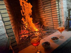 two glasses of wine sitting on a table in front of a fire at "Villa 70" Guesthouse in Gjirokastër +37 photos