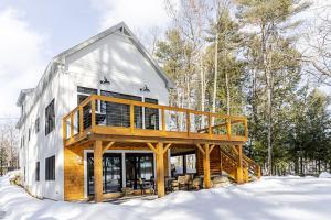a house with a deck in the snow at Long Lake-Lake Front - in Bridgton