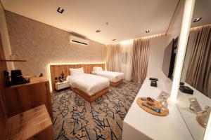 Aurion Al-Aqeeq Hotel في المدينة المنورة: غرفة فندق بها سرير وتلفزيون