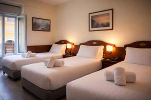 a hotel room with two beds and two lamps at Hotel Pavone in Milan