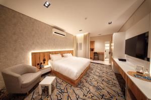 Aurion Al-Aqeeq Hotel في المدينة المنورة: غرفة فندق بها سرير وكرسي