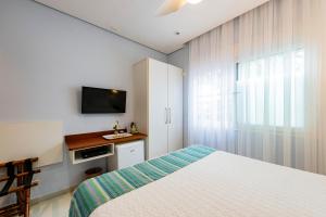 a bedroom with a bed and a tv on the wall at Pousada Alcatrazes in Juquei