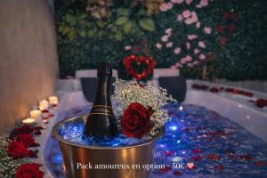 a bottle of champagne in a bucket with roses at Logement entier avec jacuzzi proche futuroscope in Naintré