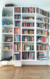a room with white bookshelves filled with books at Apartament Rutkiewicz in Łańcut