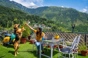 a woman sitting at a table with a dog on a balcony at PACK Mcleodganj in McLeod Ganj +106 photos
