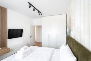 a white bedroom with a bed and a tv at Apartament Modern Urban Space - FREE Parking in Voluntari