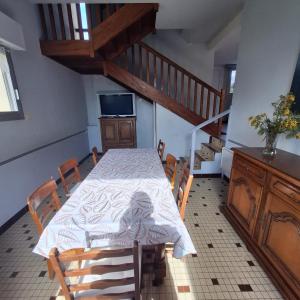 a dining room with a table with chairs and a staircase at Ty arvor in Saint-Pol-de-Léon