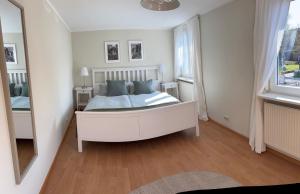 a bedroom with a white bed and a mirror at Heimelige Wohnung Bei der Stoffschmiede in Schutterwald