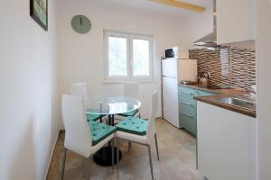 a small kitchen with a glass table and white chairs at Apartments Sonja in Šilo