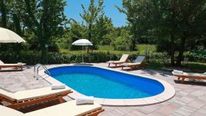 a swimming pool with two chairs and an umbrella at Apartments Sonja in Šilo