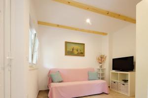 a living room with a pink couch and a tv at Apartments Sonja in Šilo