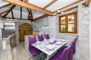 a dining room with a table and purple chairs at Villa Strnj in Živogošće