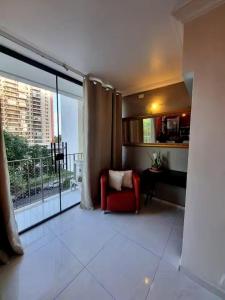 a living room with a red chair and a large window at Rio Hotel Reisdence in Água Boa