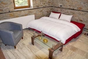 a bedroom with a bed and a chair at Stone Villa "To Petrino" in Florina