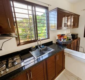 a kitchen with wooden cabinets and a sink and a window at Balbuena Countryside Villa with Private Pool in San Felipe de Puerto Plata