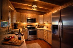 a kitchen with wooden cabinets and a stainless steel refrigerator at Bella Vista! Long range MTN views, Hot Tub, Close to town and Lake in Blue Ridge