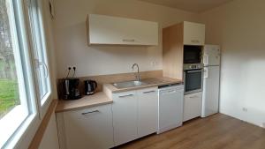 a small kitchen with white appliances and a window at Les Collines de Compreignac in Compreignac