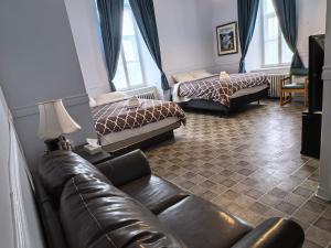 a living room with two beds and a leather couch at Auberge du Couvent in Saint-Casimir