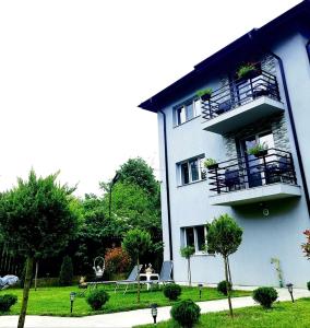 a white building with a table and a balcony at Grey in Călimăneşti +1 photo