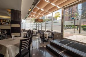 a dining room with tables and chairs and windows at Hotel Britania Miraflores in Lima