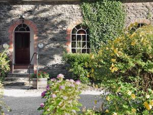 a stone house with a door and some flowers at Tuckenhay, Turbine Cottage - Fkd in Ashsprington