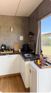 a kitchen with white cabinets and a sink and a window at Canto Flix in Brasília +9 photos