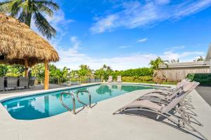 a swimming pool with chairs and a straw umbrella at Waterfront Oasis, Heated Pool, MiniGolf, TikiHut in Lake Clarke Shores