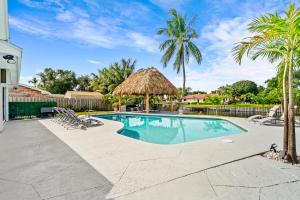 a swimming pool with a straw umbrella and palm trees at Waterfront Oasis, Heated Pool, MiniGolf, TikiHut in Lake Clarke Shores