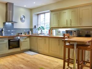 a kitchen with white cabinets and a wooden table at Barn End in Pooley Bridge
