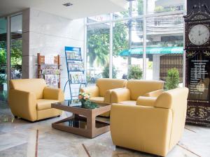 een lobby met twee stoelen en een klok in een gebouw bij Friendlytel Hotel in Hat Yai