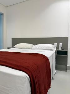 a bedroom with a bed with a red blanket on it at Areiao Park Hotel in Goiânia